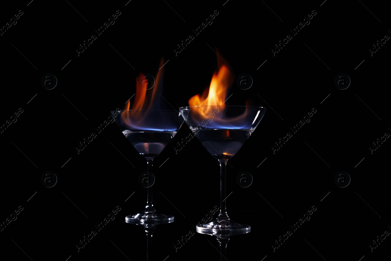 Photo of Cocktail glasses with flaming vodka on black background