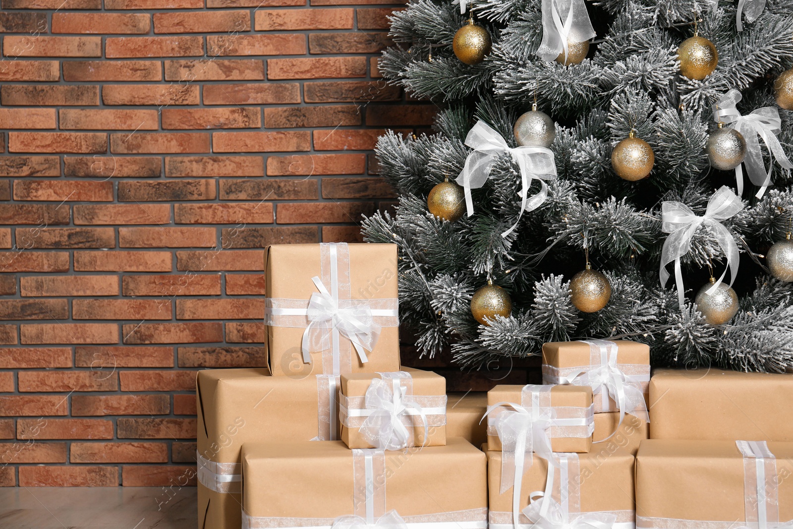 Photo of Decorated Christmas tree and gift boxes near brick wall. Space for text