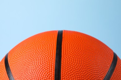Photo of One orange basketball ball on light blue background, closeup