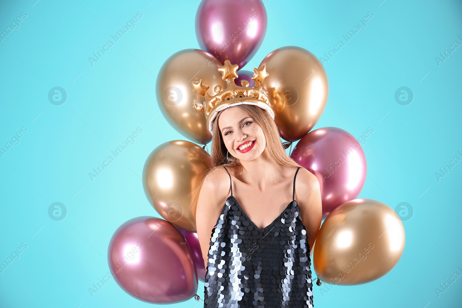 Photo of Young woman with crown and air balloons on color background