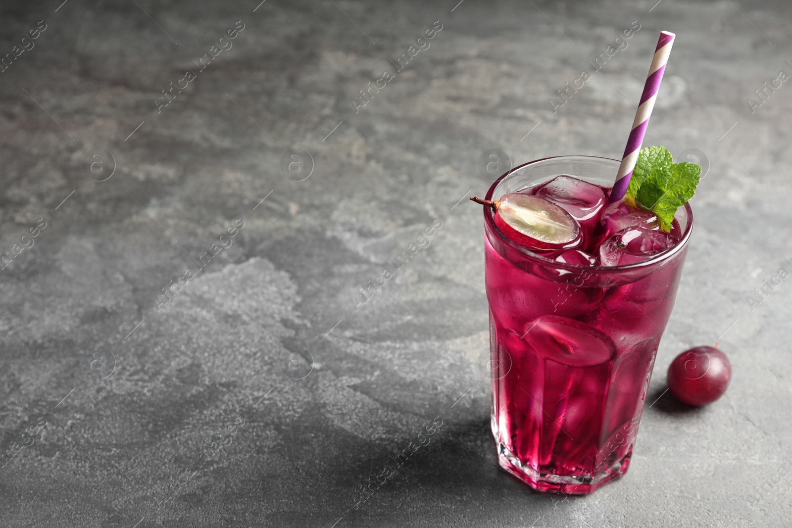 Photo of Delicious grape soda water on grey table, space for text. Refreshing drink