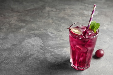 Photo of Delicious grape soda water on grey table, space for text. Refreshing drink