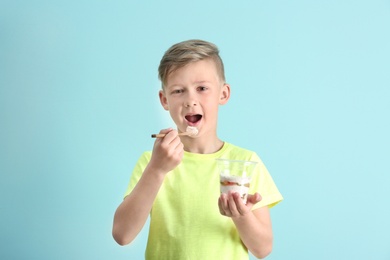 Little boy with yogurt on color background