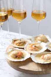 Photo of Fried scallops in shells and wine on white marble table