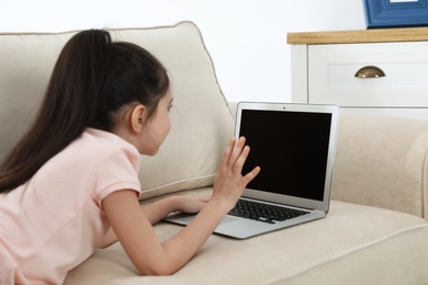 Photo of Little girl using video chat on laptop at home. Space for text