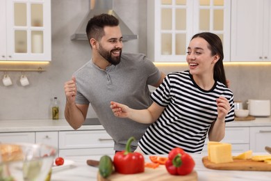 Photo of Happy lovely couple dancing together while cooking in kitchen