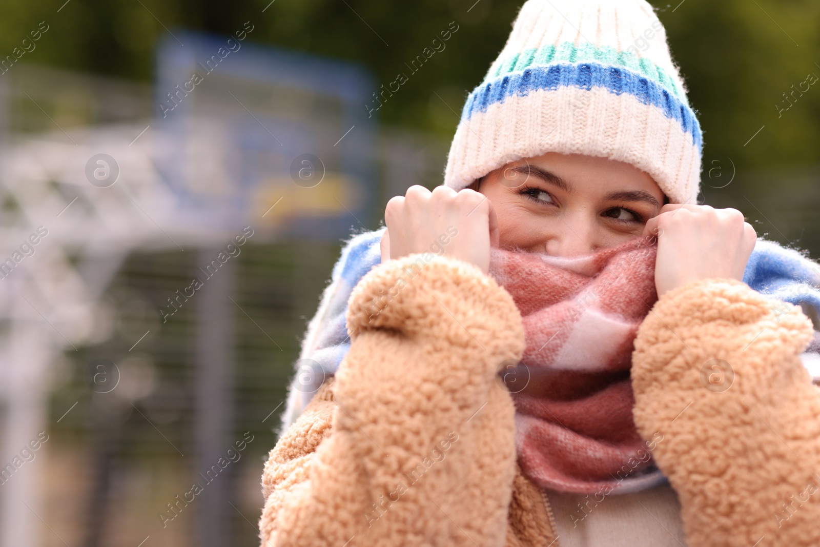 Photo of Beautiful woman in warm scarf and hat outdoors. Space for text