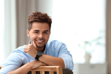 Photo of Portrait of handsome young man sitting on chair in room. Space for text