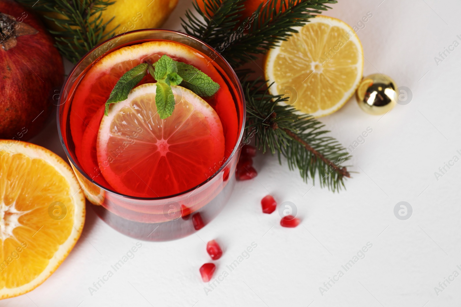 Photo of Christmas Sangria drink in glass, fir branches and fruits on white background, above view