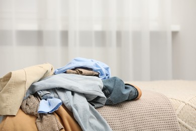 Photo of Pile of different clothes on bed indoors, space for text