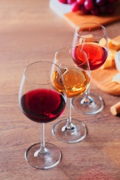 Glasses with different wines and appetizers on wooden table