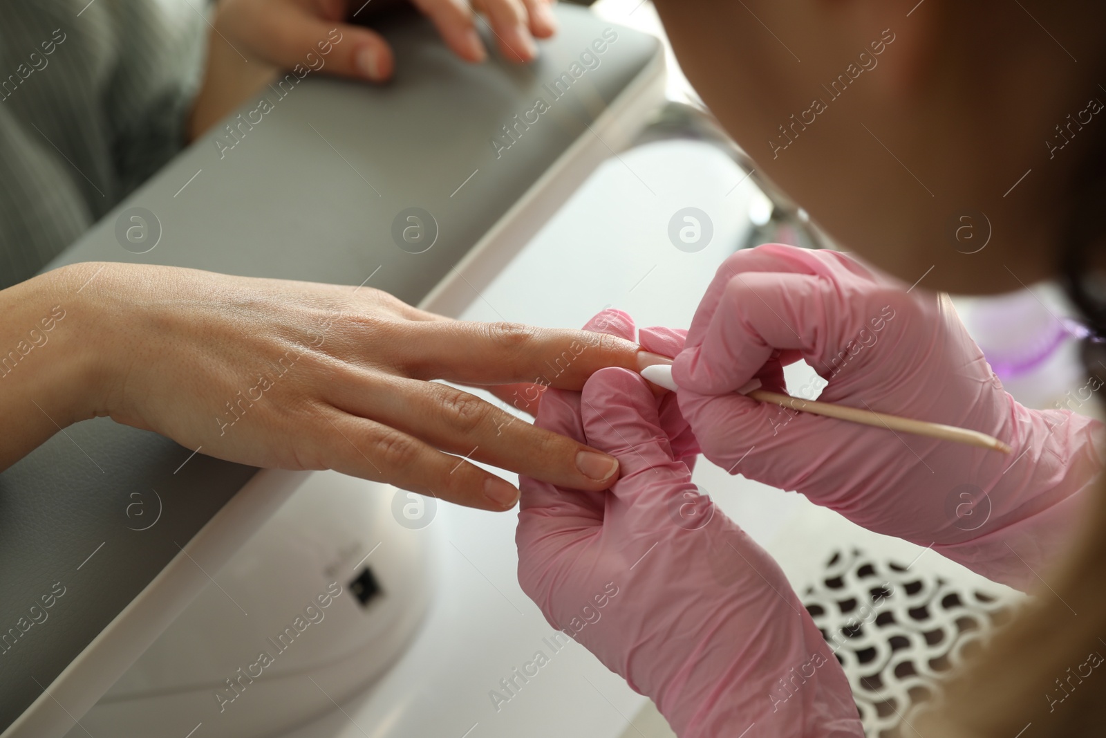 Photo of Professional manicurist working with client in beauty salon, closeup