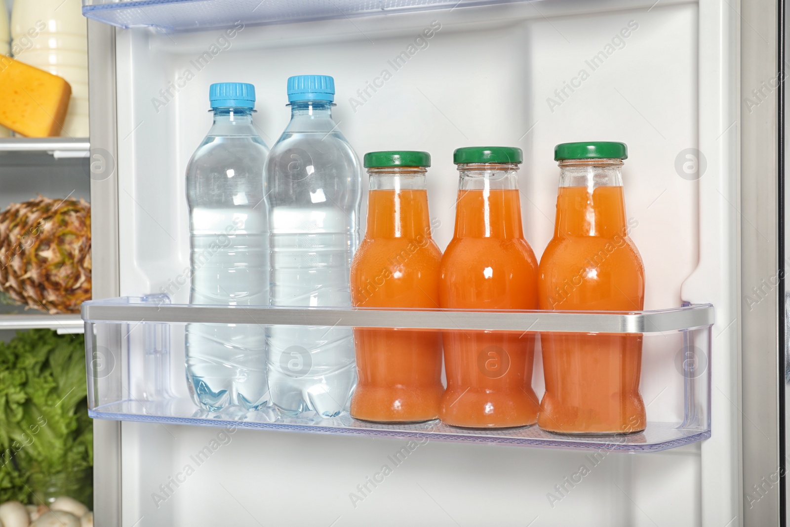 Photo of Basket with bottles of water and juice in refrigerator