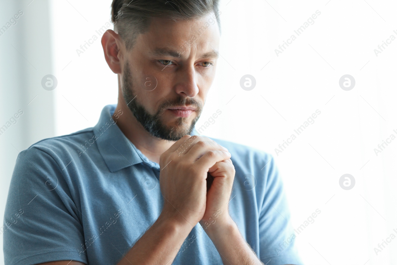 Photo of Man with hands clasped together for prayer on light background. Space for text