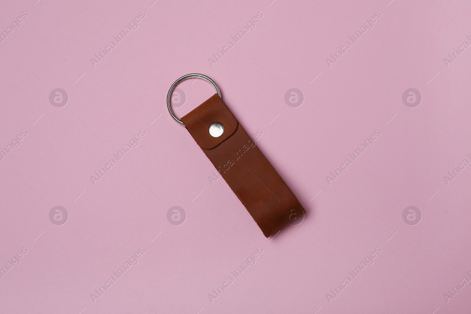 Photo of Leather keychain with Ukrainian coat of arms on pale pink background, top view
