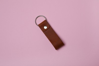 Leather keychain with Ukrainian coat of arms on pale pink background, top view