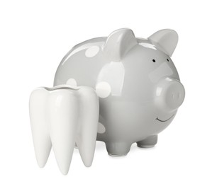 Ceramic model of tooth and piggy bank on white background. Expensive treatment