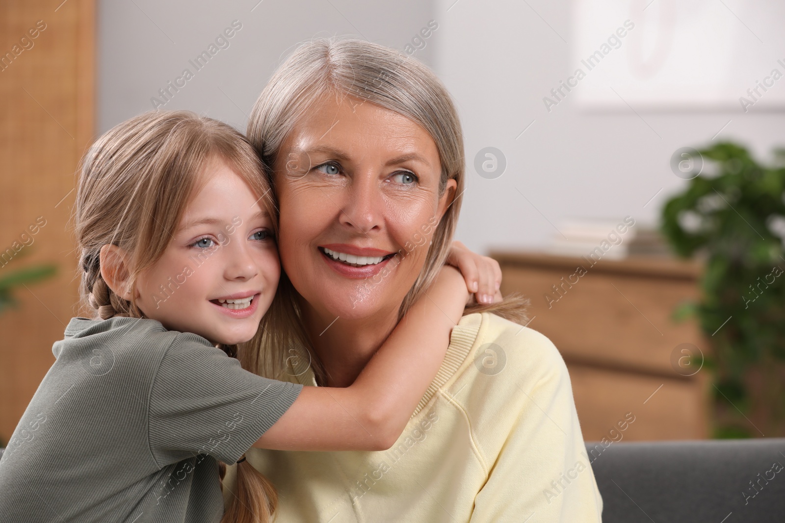 Photo of Happy grandmother with her granddaughter at home, space for text