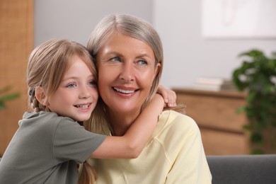 Happy grandmother with her granddaughter at home, space for text