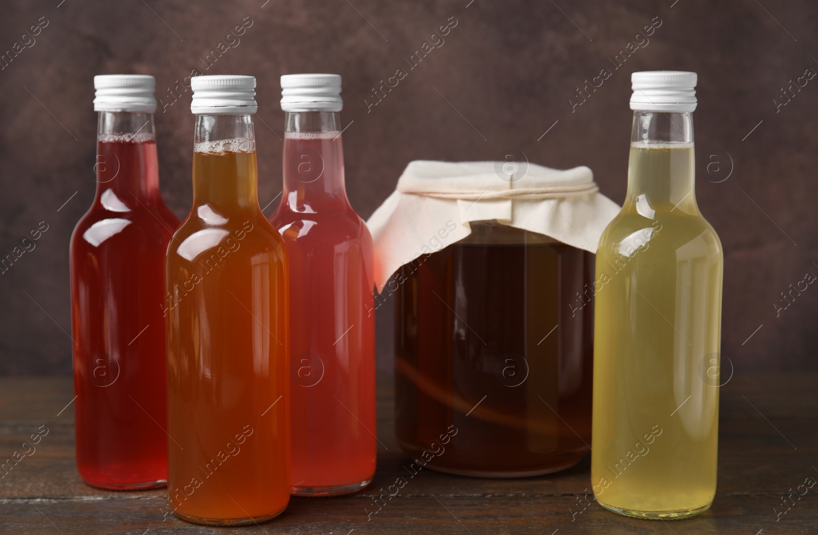 Photo of Delicious kombucha in glass bottles and jar on wooden table