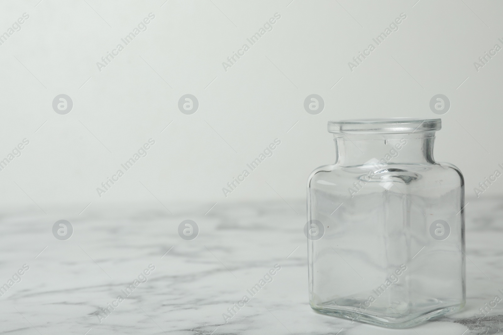 Photo of Empty glass jar on white marble table, space for text