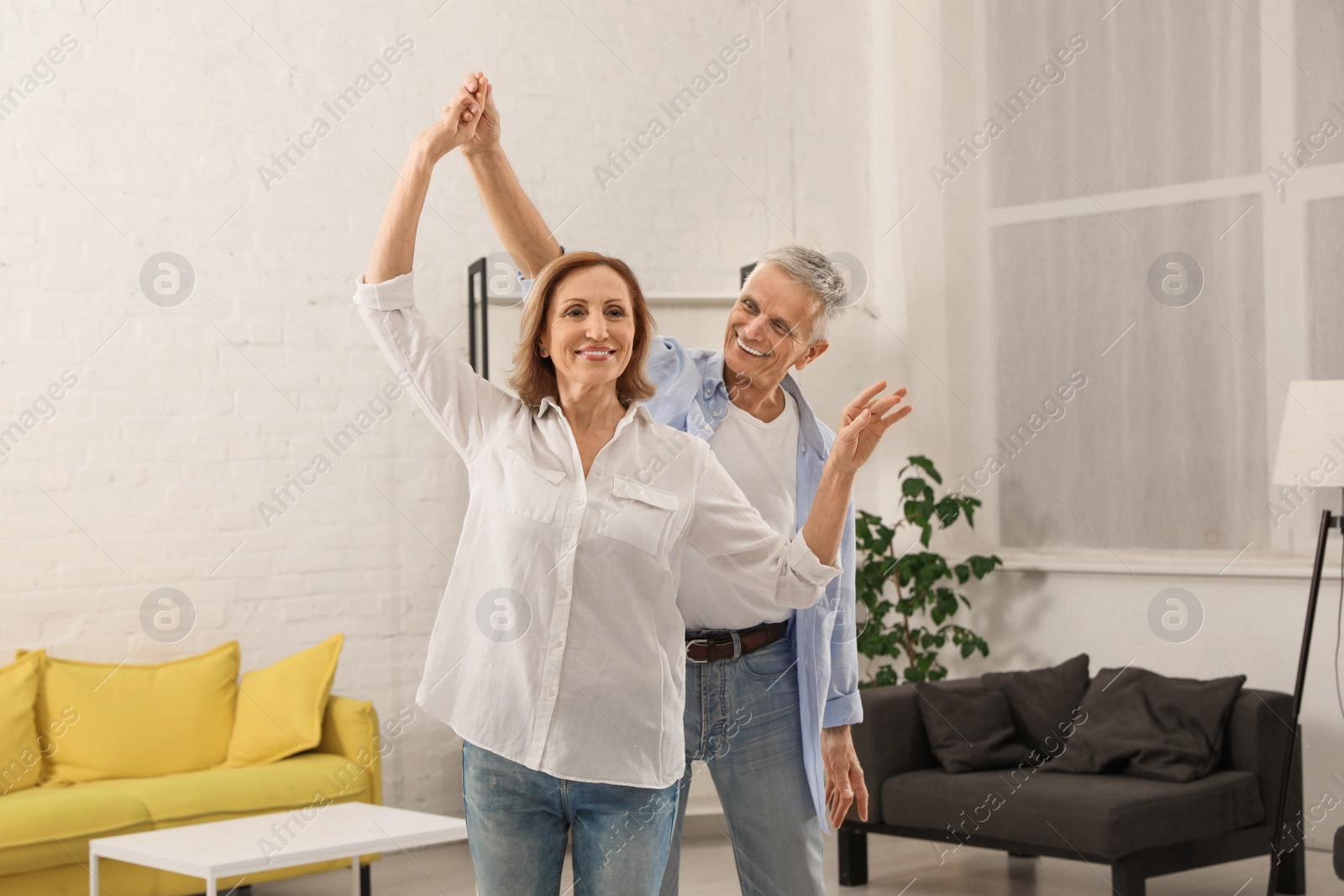 Photo of Happy senior couple dancing together in living room