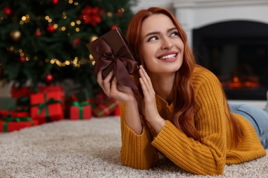 Photo of Happy young woman with Christmas gift at home