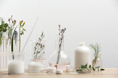 Photo of Herbal cosmetic products, laboratory glassware and ingredients on wooden table