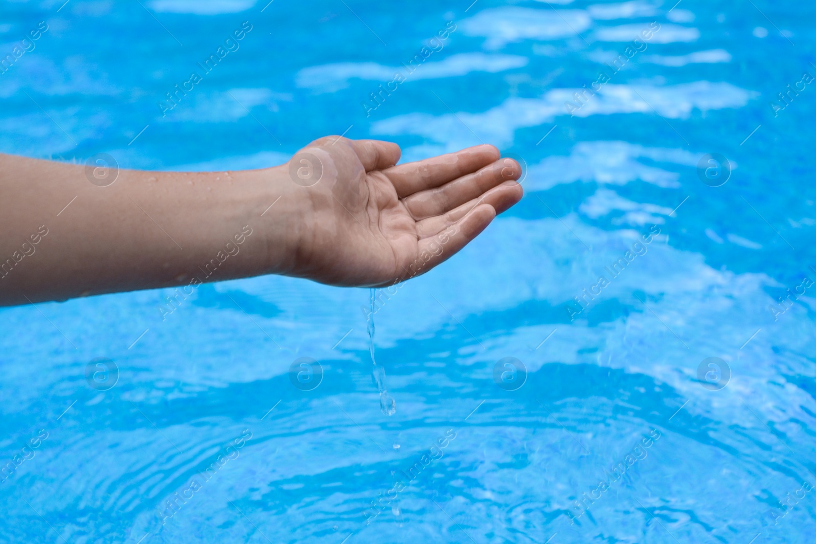 Photo of Girl pouring water from hand in pool, closeup