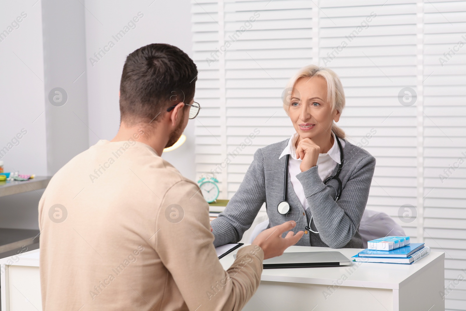 Photo of Doctor consulting patient at white table in clinic