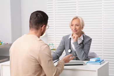 Doctor consulting patient at white table in clinic