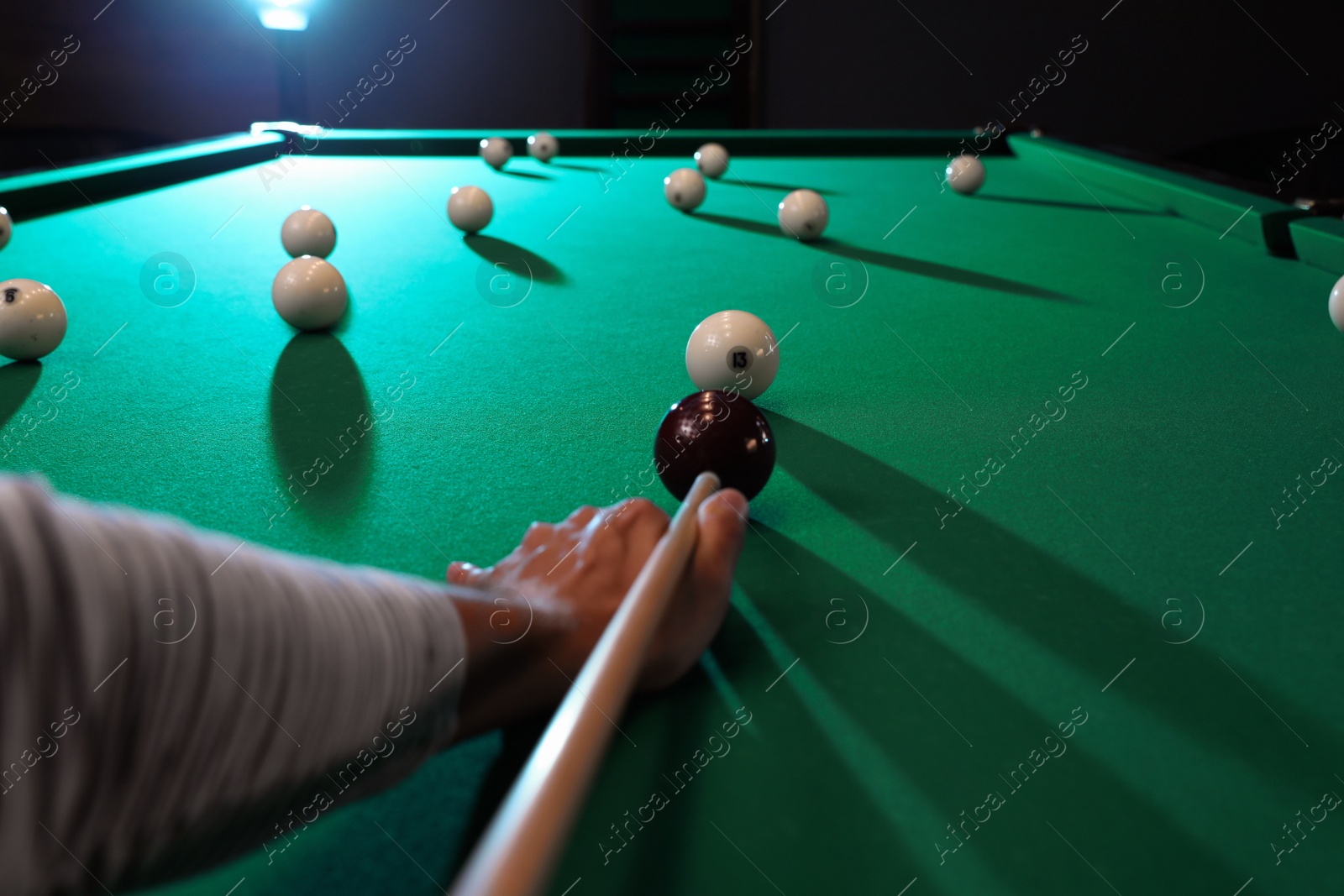 Photo of Young man playing Russian billiard indoors, closeup