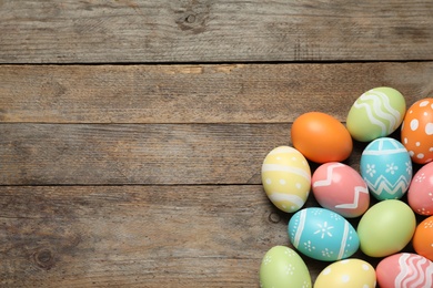 Many colorful painted Easter eggs on wooden background, top view. Space for text