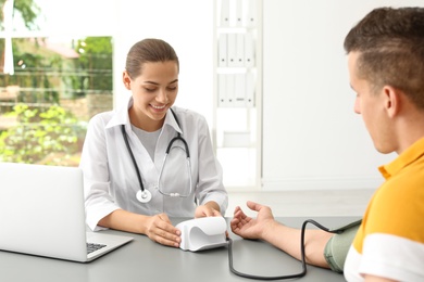 Doctor checking patient's blood pressure in hospital