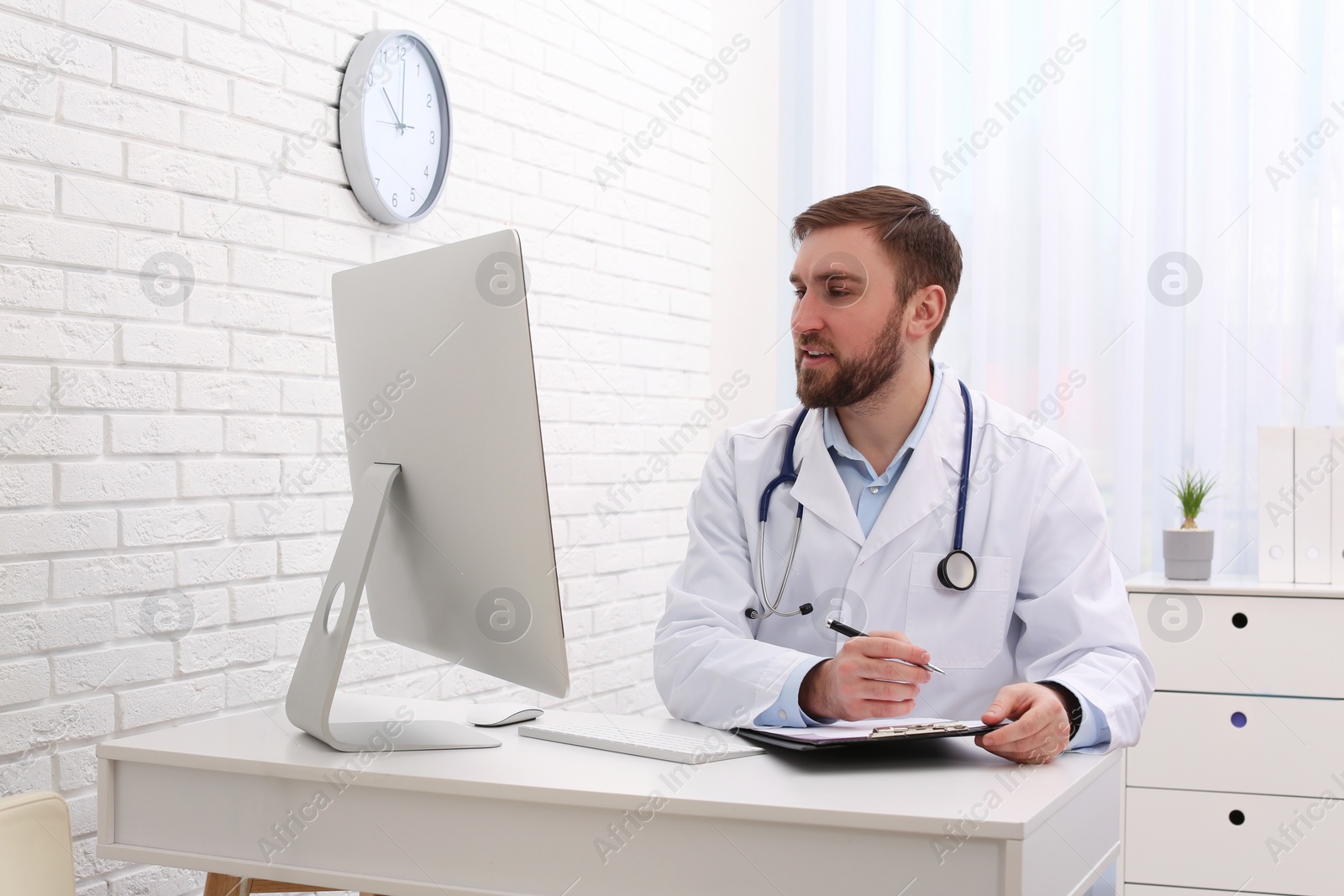 Photo of Pediatrician consulting patient online at table in clinic