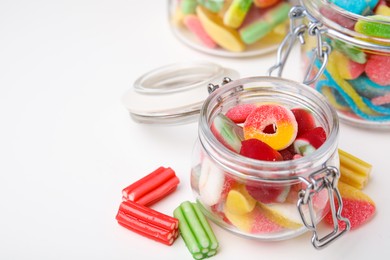 Tasty jelly candies in jars on white table