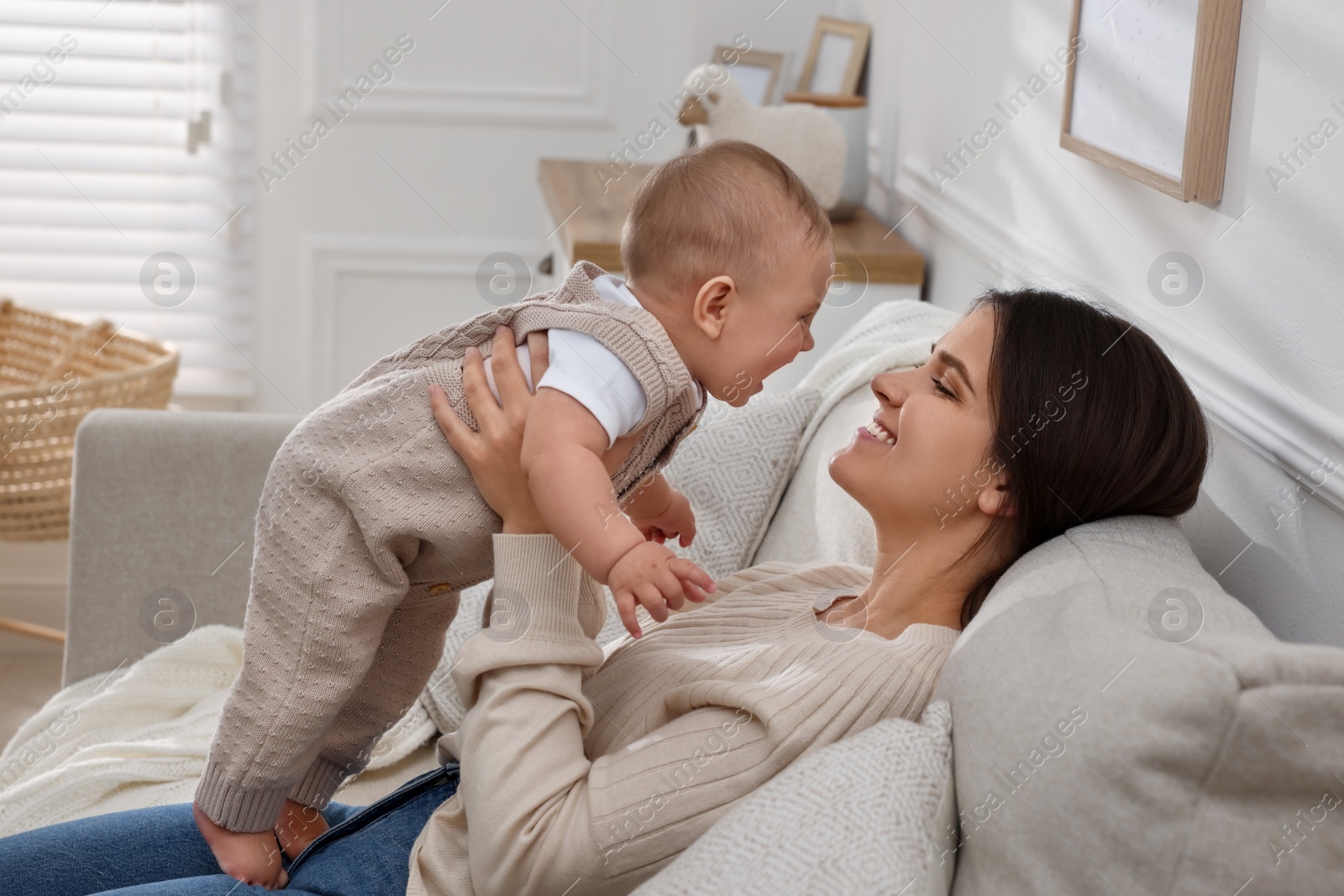 Photo of Happy young mother with her baby on sofa in living room