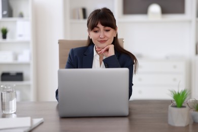 Woman watching webinar at wooden table in office