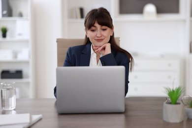 Photo of Woman watching webinar at wooden table in office