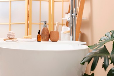 Different personal care products and accessories on bath tub in bathroom