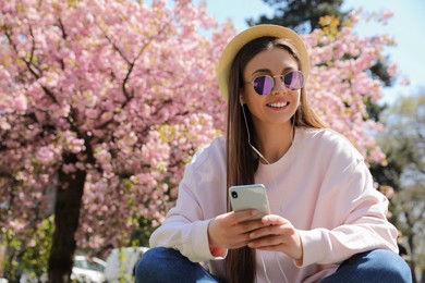 Photo of Young woman listening to audiobook in park