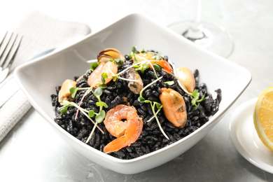 Photo of Delicious black risotto with seafood in bowl on table, closeup