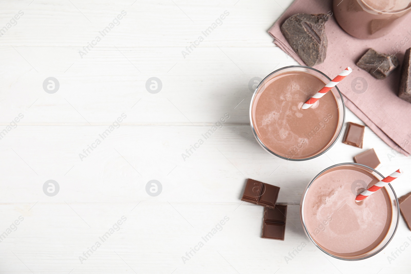 Photo of Delicious chocolate milk on white wooden table, flat lay. Space for text