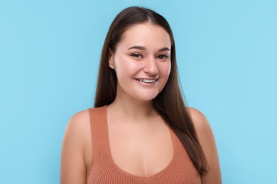 Smiling woman with dental braces on light blue background