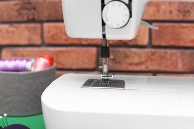 Modern sewing machine near brick wall, closeup