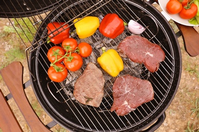 Photo of Modern grill with meat and vegetables outdoors