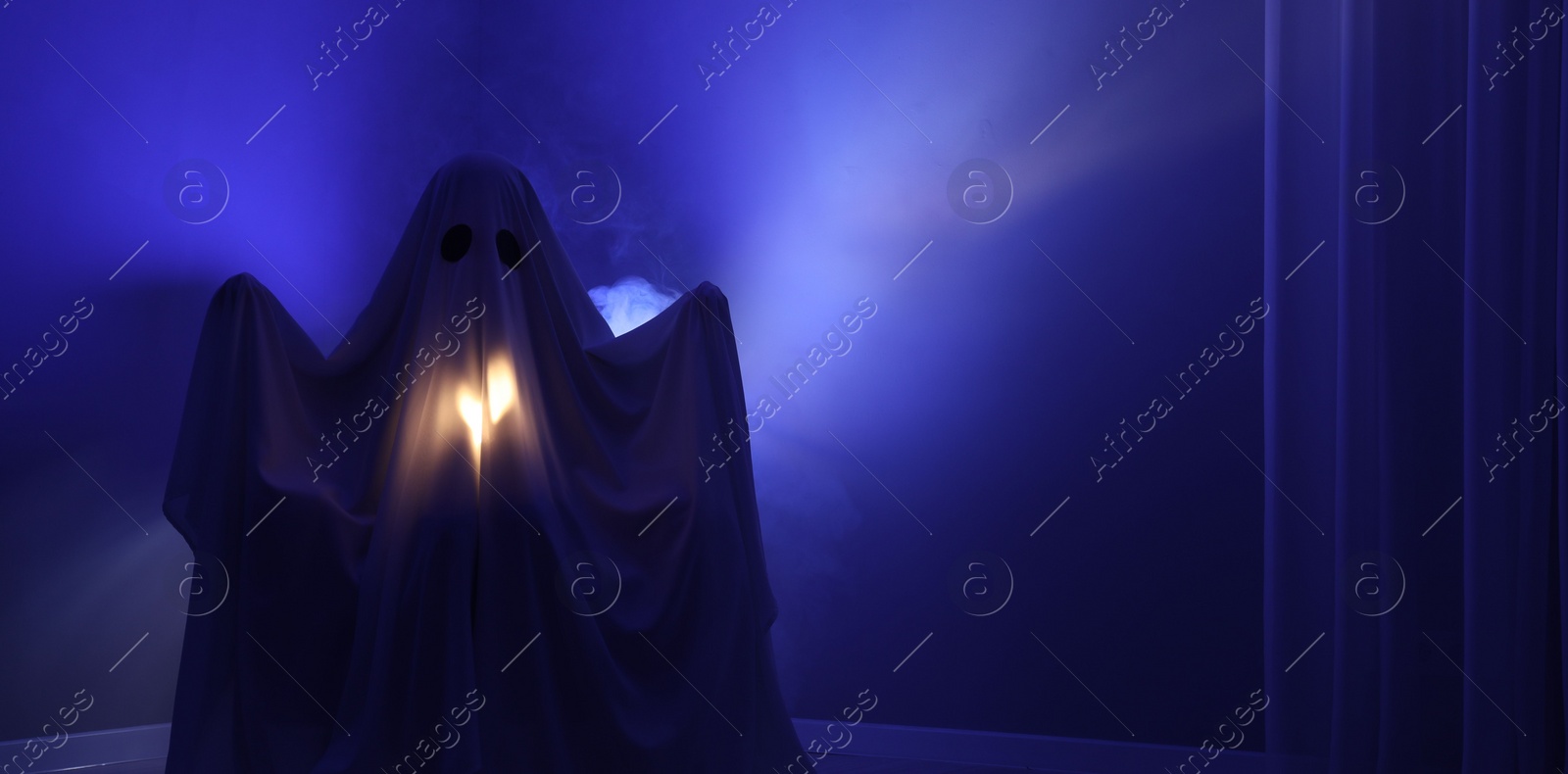 Photo of Creepy ghost. Woman covered with sheet in blue light, space for text