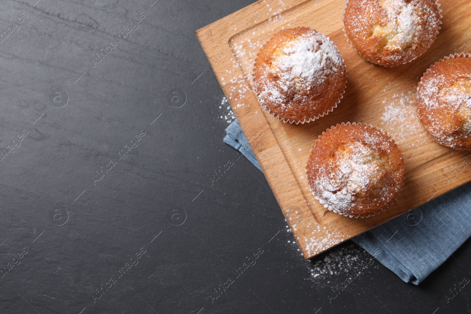 Photo of Delicious sweet muffins on black textured table, top view. Space for text