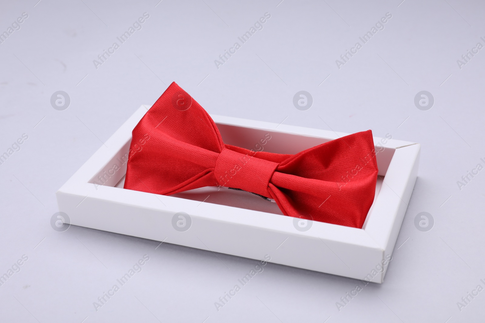 Photo of Stylish red bow tie in box on white background