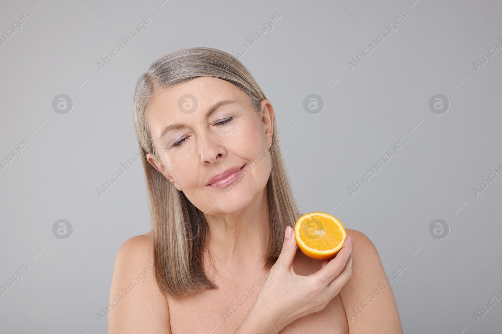 Photo of Beautiful woman with half of orange rich in vitamin C on grey background